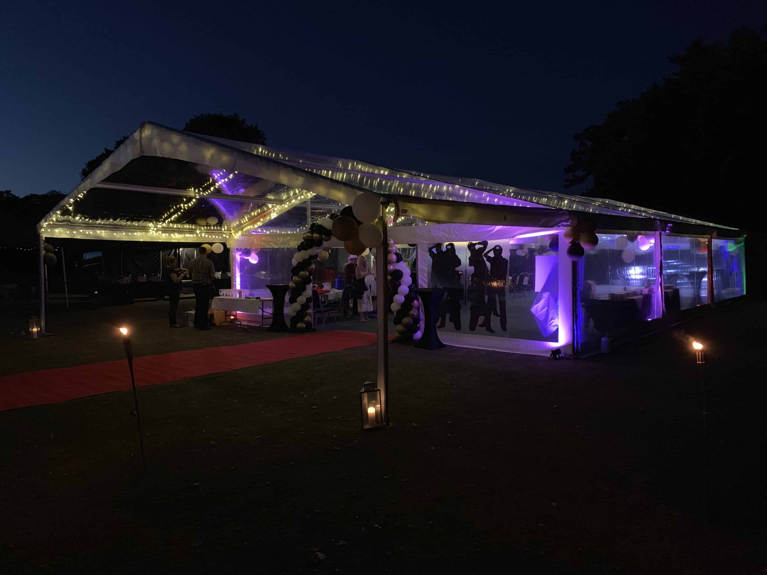 Clearspan marquee illuminated with purple lighting for an evening event.
