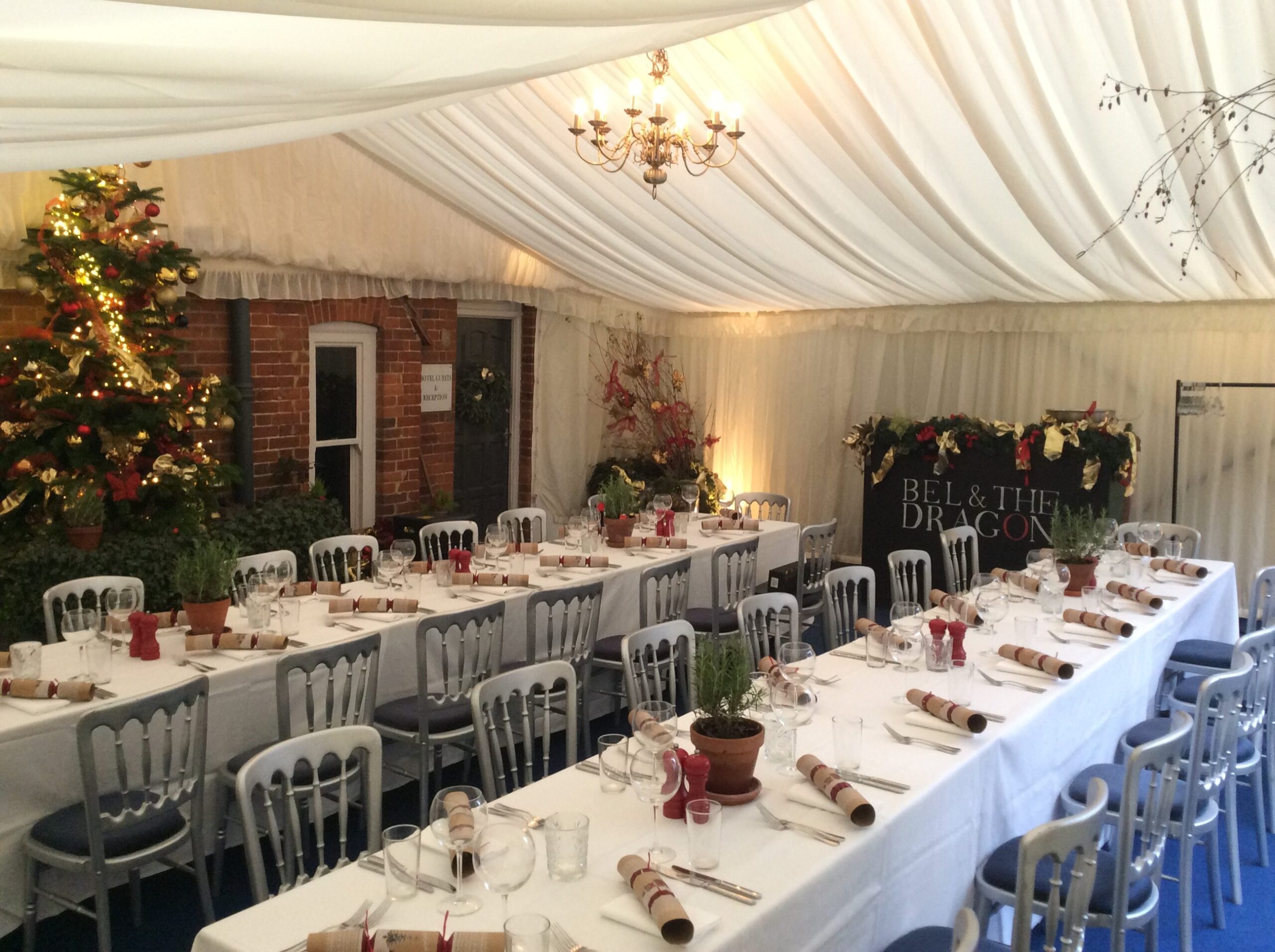 Christmas marquee interior with long dining tables, chandeliers and festive decorations.