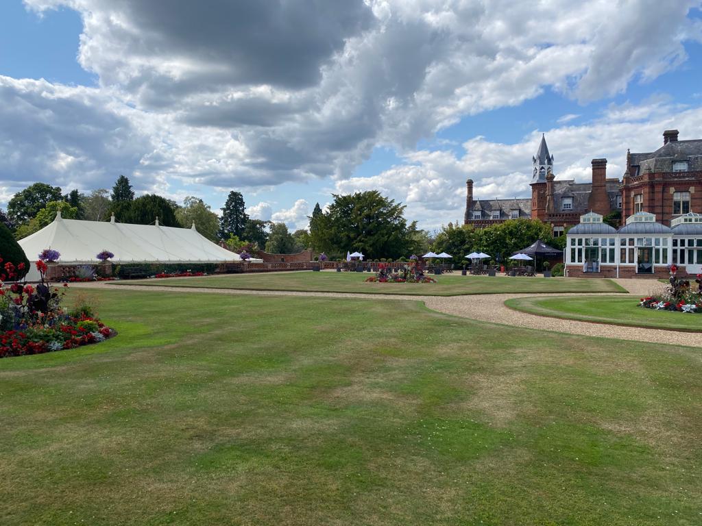 Garden event venue with marquee on the lawn beside a country house under dramatic cloudy skies.
