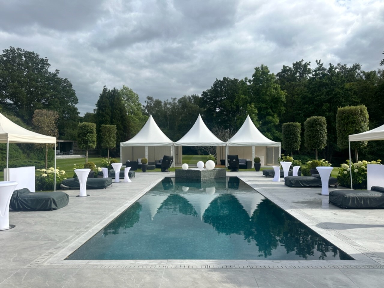White event pagodas beside a swimming pool at a luxury garden party venue