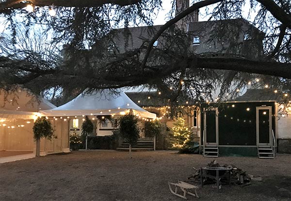Evening garden event with lit marquee awning and outdoor seating area