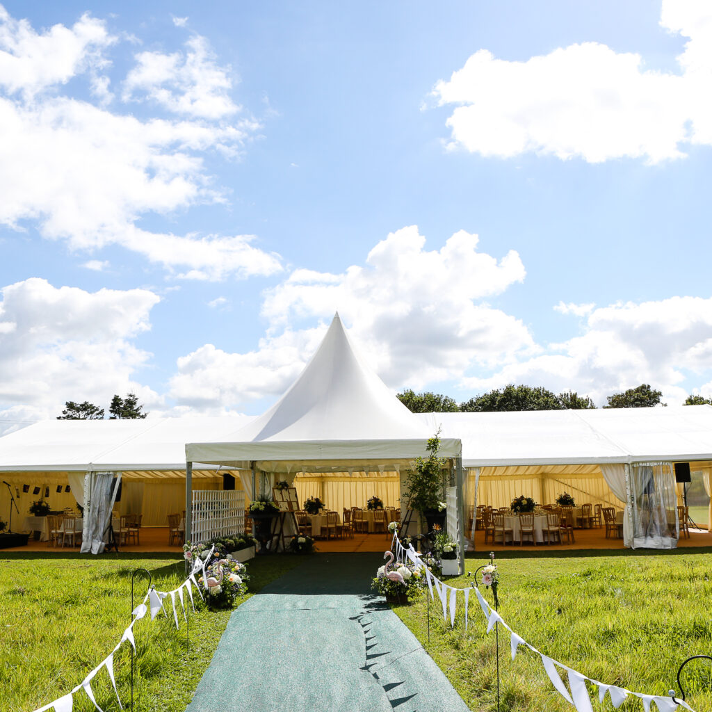 12m wide frame marquee with central pagoda entrance canopy, clear window walls and elegant interior, creating a spacious wedding venue in a countryside setting.