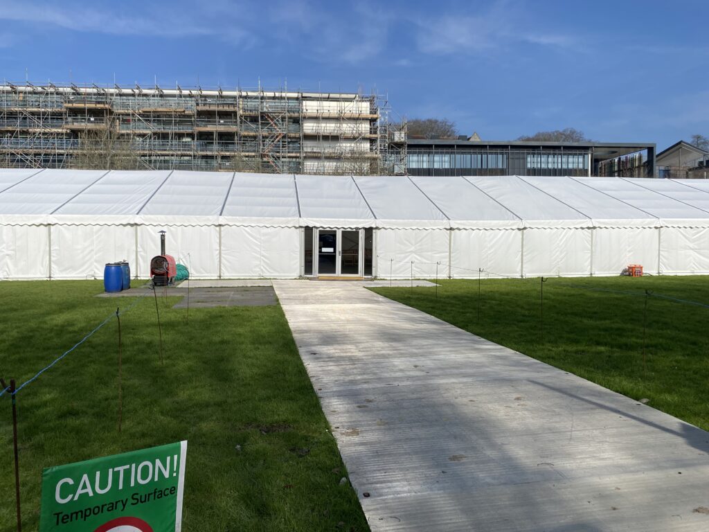 Temporary vehicle access roadway leading to a marquee installation, providing safe ground protection for event vehicles and equipment on grass.